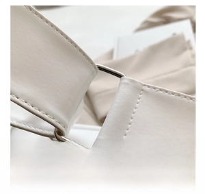Detail of silver metal hardware rings and stitching on white soft leather tote bag