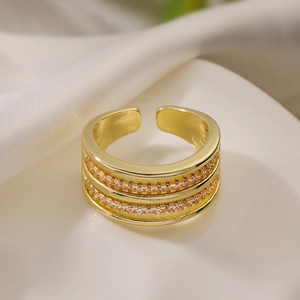 Minimalist double-row gold open ring with pink zircon stones on a beige fabric background