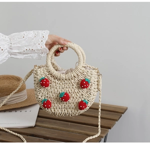 Detail der handgewebten Strohtasche mit 3D-Häkel-Erdbeeren und Kordelzug-Innentasche