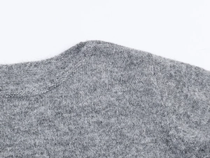Gros plan sur le pull en maille ajourée gris doux avec texture à volants fins