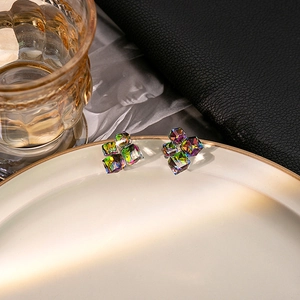 Macro shot of cubic crystal earrings with aurora multi-color refraction on a white plate