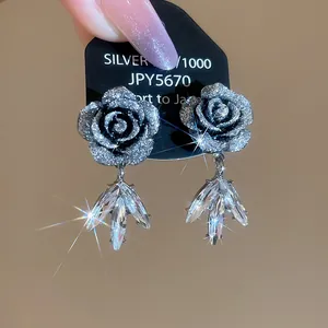 Dettaglio di orecchini a fiore in resina nera con glitter argento e cristalli lucenti