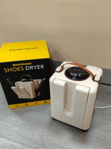 Detail of white shoe dryer with leather handle, folding ducts, and digital timer display