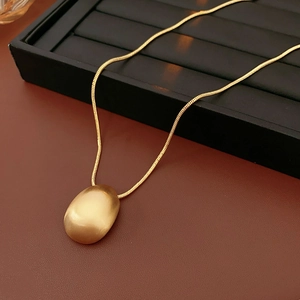 Détail du pendentif ovale en or brossé sur une fine chaîne de style serpent chic