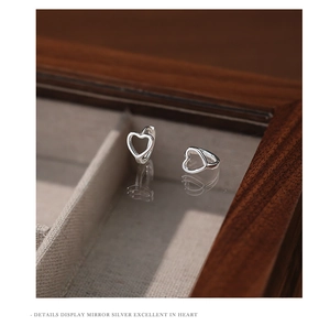Macro shot of silver heart hoop earrings reflecting on a mirror inside a wooden box
