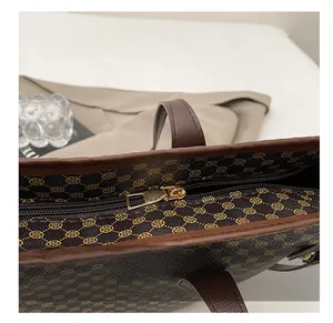 Detail view of smooth golden zipper and clover print on brown tote bag material