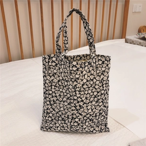 Detailed close-up of a black canvas tote bag with white floral print on a white surface
