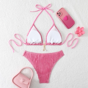 Detail of pink ruffled bikini with golden star charm and pearl ring on soft fabric