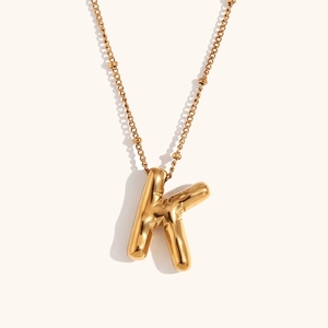 Macro detail of 18K gold plated balloon letter K pendant on a satellite bead chain