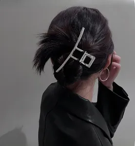 Detail showing a silver geometric metal hair claw clip styled on a model's back hair