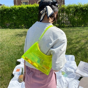 Neon yellow transparent PVC baguette bag shown on model in an outdoor picnic setting
