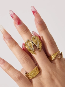 Close-up of gold rings with zircon wings and brown gemstone on female hand