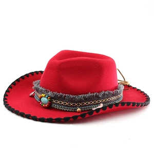 Detail of red wool felt cowboy hat with woven band, tassels, and turquoise stone accent