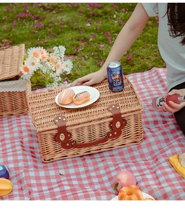 Dettaglio di un cesto da picnic in vimini fatto a mano con cinghie in pelle su un telo
