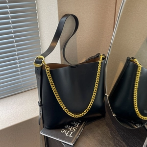 Minimalist black leather bucket bag with chunky gold chain strap and wide leather strap