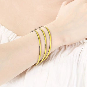 Close-up of three minimalist silver rings with yellow enamel dripping on female wrist