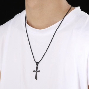 Detail of a black stainless steel cross necklace with a small diamond on a male model