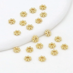 Macro detail of 18K gold-plated snowflake spacers and floral metal beads for DIY jewelry