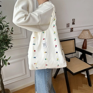 Detail of colorful floral embroidery and textile label on a white canvas tote bag