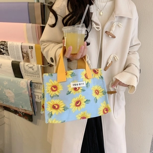 Detail of light blue canvas lunch bag with yellow sunflower print and durable handles