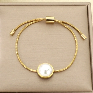 Détail du bracelet chaîne serpent dorée avec grosse perle blanche et fermoir coulissant