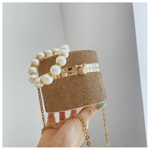 Detailed view of luxury gold rhinestone cylinder evening bag with large pearl handle