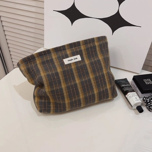 British style retro plaid canvas makeup bag with a minimalist woven label on a desk