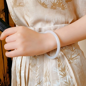 Close-up of a round white translucent jade bangle worn with elegant Chinese style attire