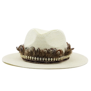 Detail of straw boater hat featuring brown feathers and gold skull metal accents