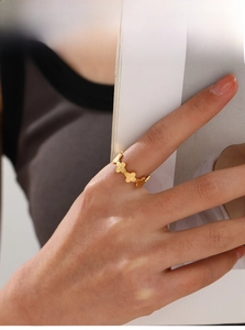 Detail van 18K vergulde bloemring met klavermotieven aan de hand gedragen