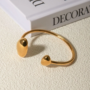 Macro scatto del bracciale rigido aperto irregolare in oro 18k su pietra bianca