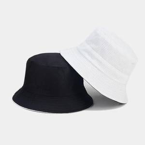 Detail of corduroy and cotton textures on reversible minimalist bucket hats in black and beige