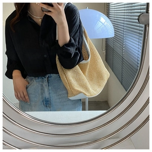 Mirror selfie showing a woven straw tote bag with white faux leather trim and shoulder strap