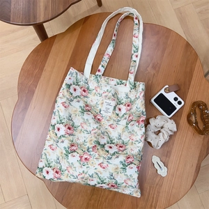 Borsa tote in tela a fiori vintage appoggiata su un tavolo in legno con spalline