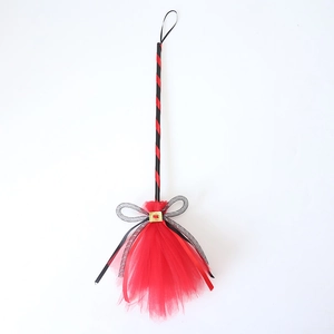 Close-up of red mesh Halloween witch broom with silver bow and gold buckle detail