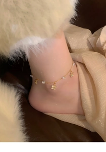 Close-up of a gold flower anklet with crystals worn on a model's ankle for a luxury look