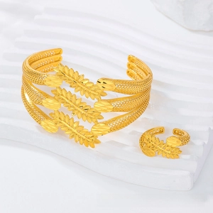 Detail of gold hollowed wheat leaf bangle and ring set with intricate carved textures