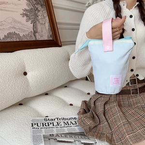 Detail view of the pastel canvas storage bag with pink handle and woven brand label