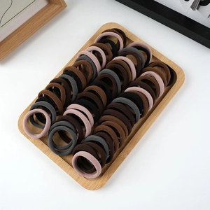 Macro shot of assorted brown, grey, and black elastic hair ties on a bamboo tray