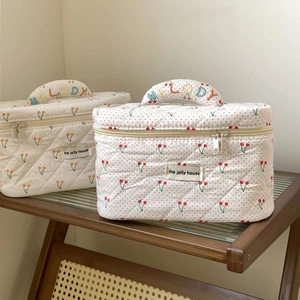 Detailed close-up of quilted cherry pattern cosmetic bag with Melody embroidered handle