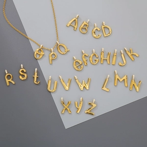 Detailed view of gold plated A-Z initial pendants with sparkling zircon stone accents