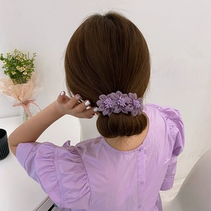 Dettaglio dell'accessorio per capelli a fiori viola con perline sulla testa del modello