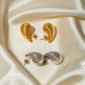 Macro shot of 18k gold and silver stainless steel earrings with striped spiral texture