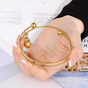 Detail shot of a 18K gold plated heart bangle with round bead accents on a woman's wrist