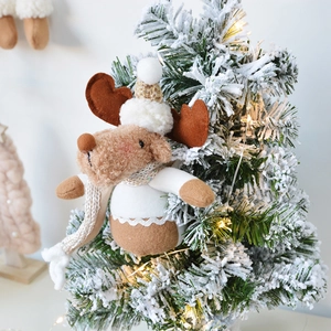 Plush Christmas reindeer ornament with white knit hat and scarf on a festive snowy tree