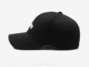 Side view detail of a black cotton baseball cap with white embroidery and curved brim