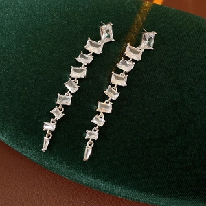 Macro shot of silver square cubic zirconia tassel earrings on dark velvet background