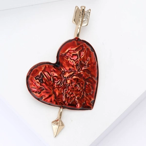 Exquisite red enamel heart brooch with gold arrow piercing on a clean white background