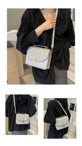 Detail of light grey quilted crossbody bag featuring a golden circular metal lock closure