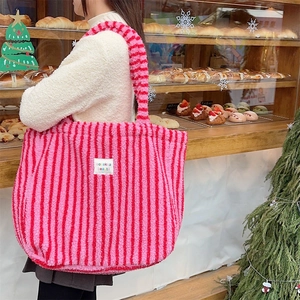 Détail du sac cabas en peluche à rayures rose et rouge montrant la texture douce et l'étiquette